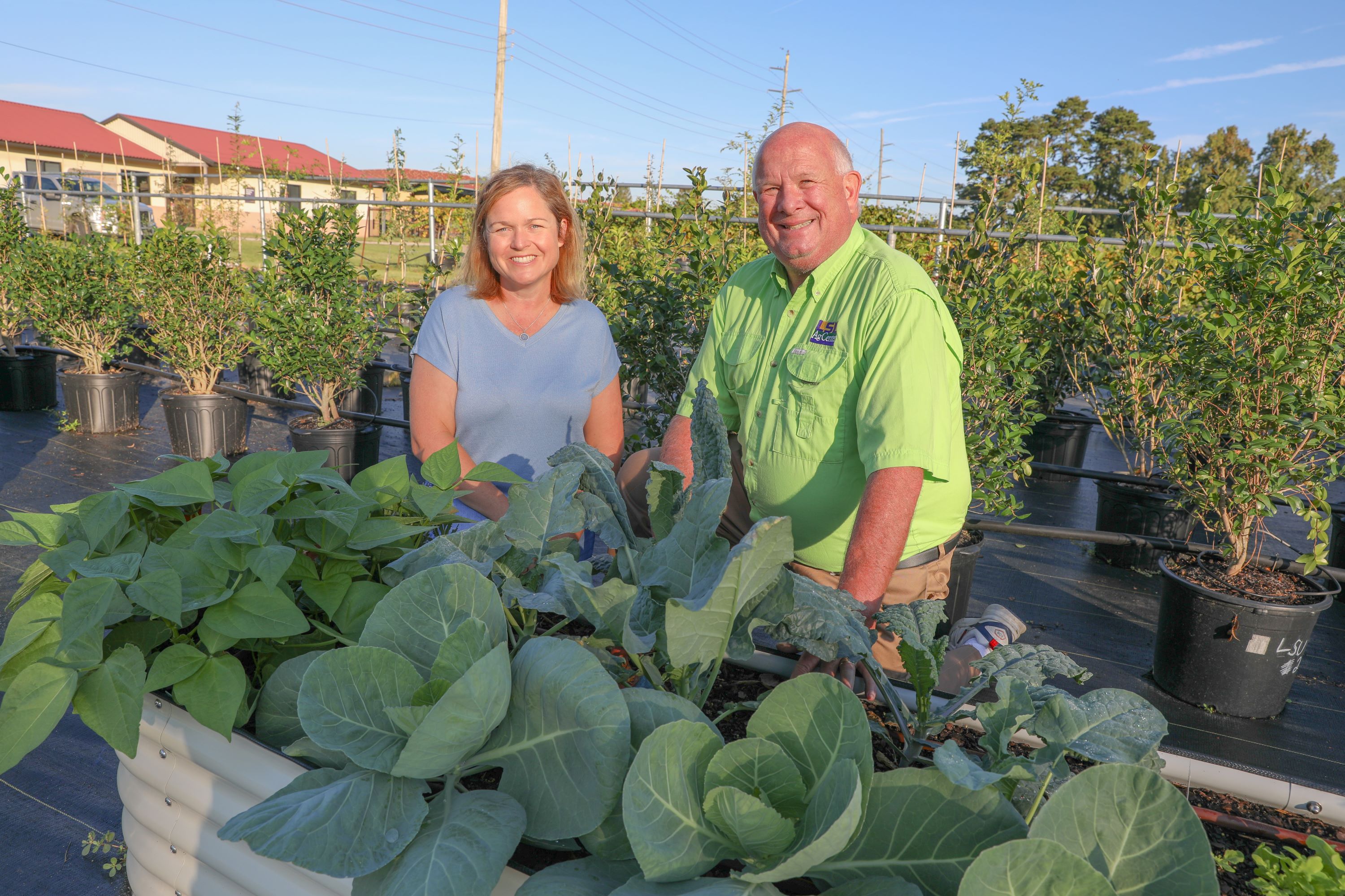 faculty in front of raised garden bed