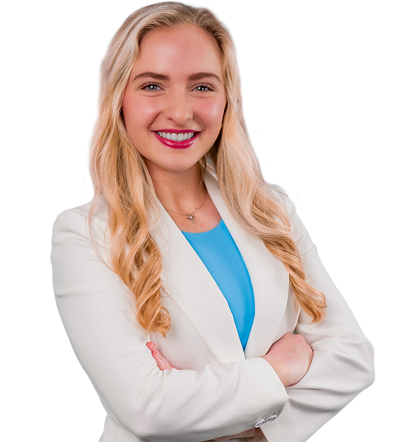 Christen Chehardy's arms are crossed in this headshot. She wears a white suit and aqua top with a bright smile.