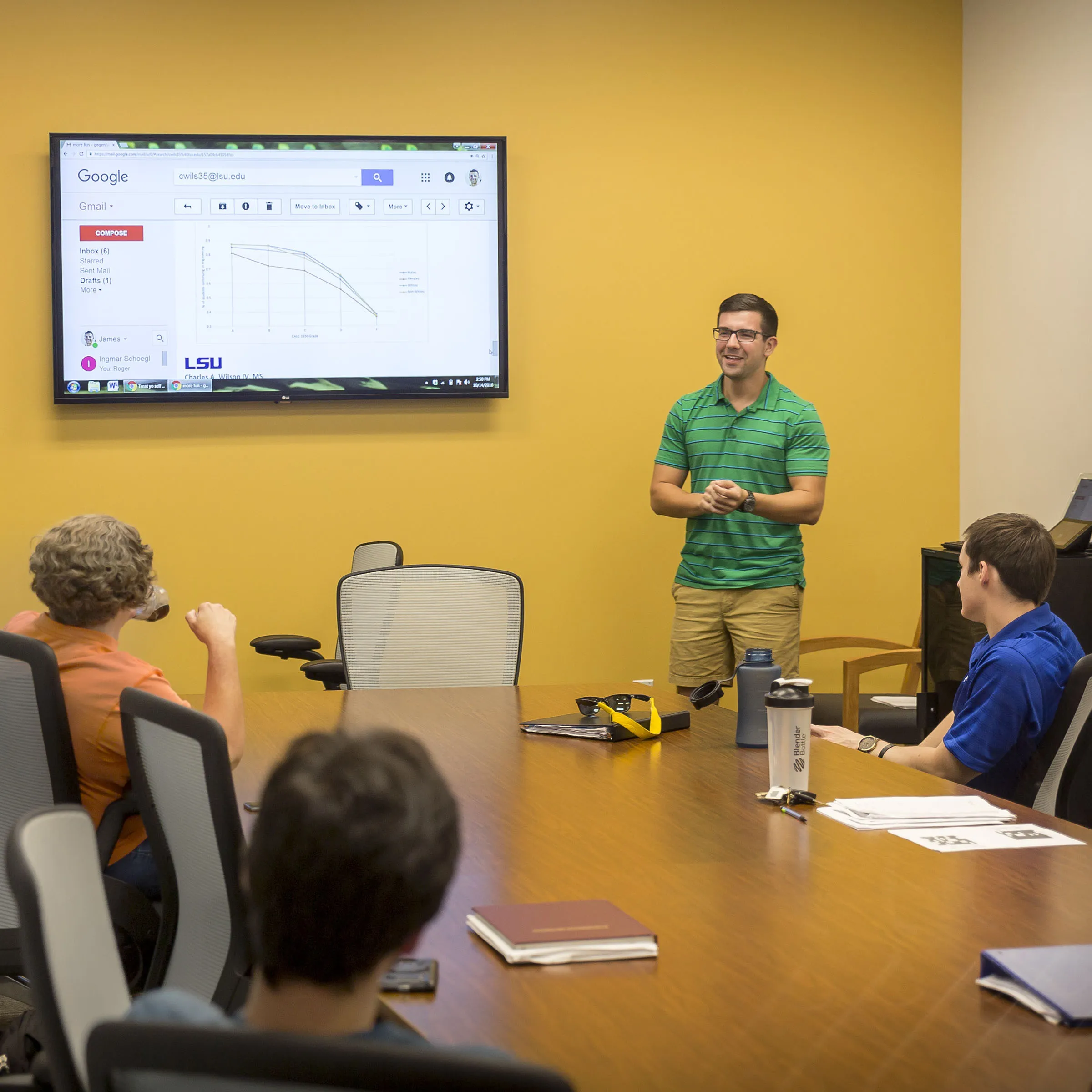 A student in a conference room presenting in front of a screen