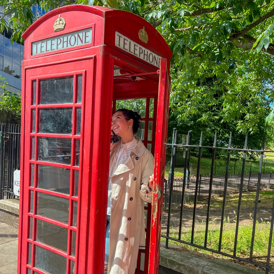 student smiles in a classic London phone booth