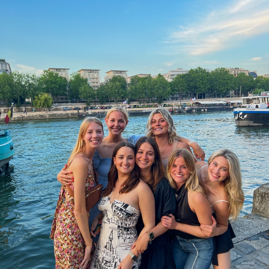 group of students smile in front of a river